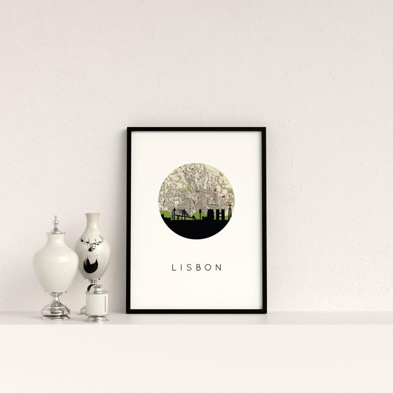 Framed Lisbon art print on a shelf alongside decorative silver and white ceramic vessels.