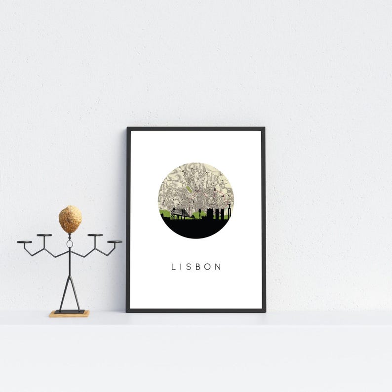 Framed Lisbon print resting on a white shelf next to a stylized metal candle holder with a wooden head.