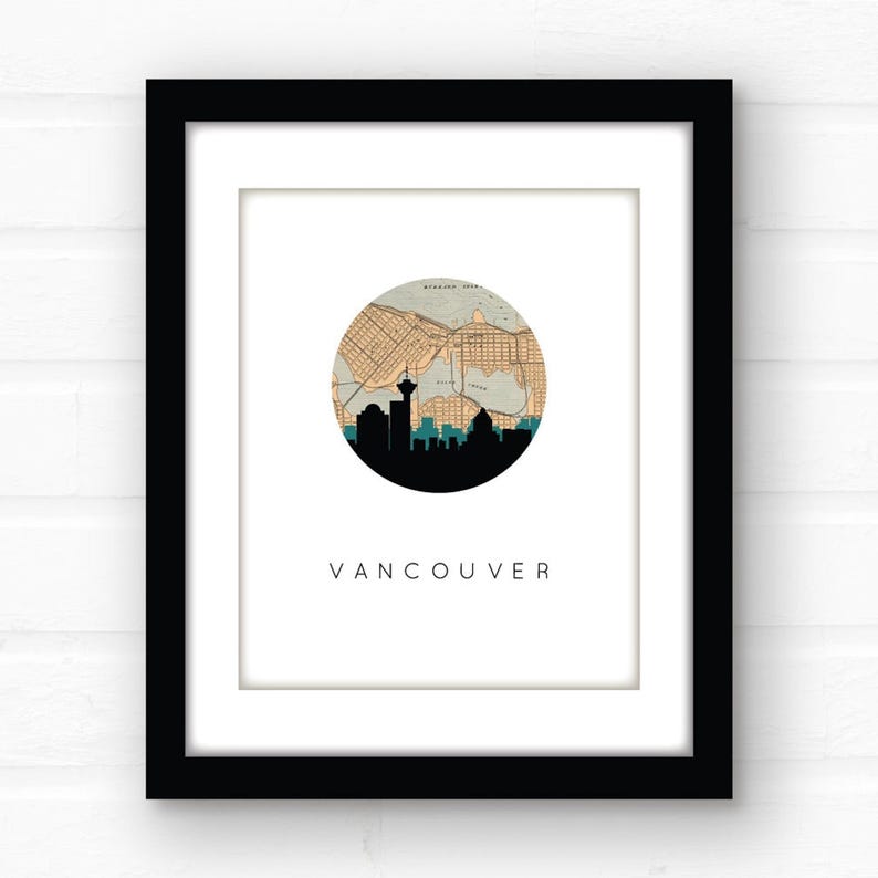 Close-up view of the framed Vancouver art print with a black frame and white mat board, hanging against a white brick wall.