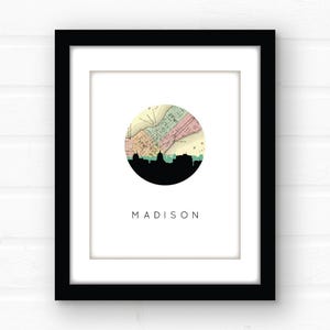 A framed Madison map print hangs against a white brick wall.