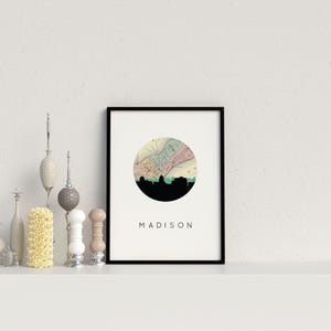 A framed Madison map print is displayed on a white shelf alongside various decorative figurines and bottles.