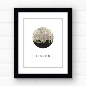Close-up of a framed Lisbon print with a white mat against a white brick wall.