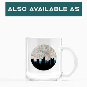 May include: Clear glass mug featuring a black and blue skyline silhouette against a circular map design. The mug has a handle and the text "ALSO AVAILABLE AS" is at the top.
