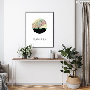 A framed Madison map art print hangs on a white wall above a console table featuring plants and decorative objects.