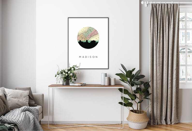 A framed Madison map art print hangs on a white wall above a console table featuring plants and decorative objects.