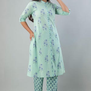 May include: A mint green two-piece outfit featuring a long-sleeved tunic and matching pants. The tunic has a mandarin collar and a button-down front. Both pieces are adorned with a blue floral pattern. The outfit is made of a lightweight fabric.