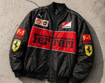 May include: Black bomber jacket with red and white accents. Features the Ferrari logo and F-1 patches. Includes sponsor logos like Shell and UPS. A stylish, sporty design.