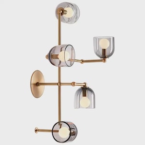 May include: Modern wall sconce with a brass finish and multiple clear glass shades. The sconce features a unique design with several light bulbs, creating a stylish and contemporary lighting fixture. The fixture is mounted on a wall.