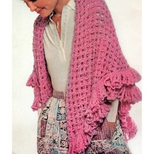 May include: A pink crocheted shawl with a lacy pattern and fringe trim. The shawl is draped over a person's shoulders.