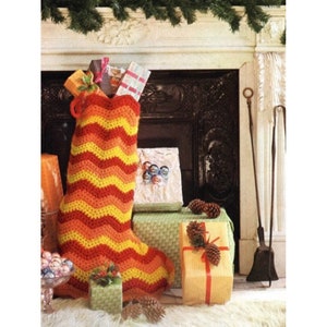 May include: A crocheted Christmas stocking with a wavy pattern in red, orange, and yellow hanging by a fireplace. The stocking is filled with wrapped gifts and is surrounded by other gifts and pine cones.