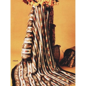 Puede incluir: Una manta de crochet a rayas en tonos marrones, blancos y naranjas. La manta está drapeada sobre una silla y tiene un borde de flecos.