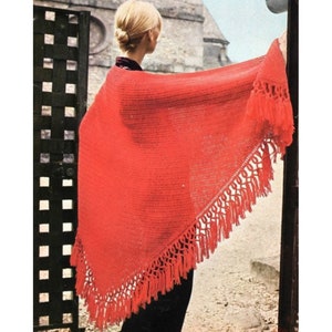 May include: A bright red crocheted shawl with a fringe border. The shawl is draped over a person's shoulders.