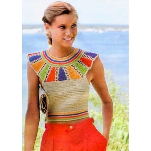 May include: A cream-colored crochet top with a colorful yoke featuring blue, orange, green, and red accents. The top has a round neckline and short sleeves. The person is wearing red pants.