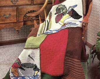 May include: A crocheted throw blanket with a patchwork design featuring images of ducks and other wildlife. The blanket is brown, red, green, and white.