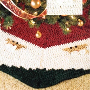 May include: A red, white and green knitted Christmas tree skirt with a Santa Claus face design. The skirt has a red top border, a white middle section and a green bottom border.