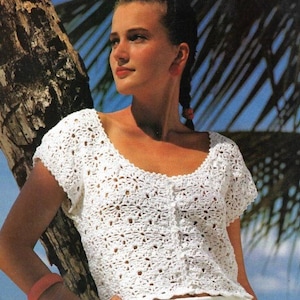 May include: White crochet top with a scoop neck and short sleeves. The top has a button fastening at the front.