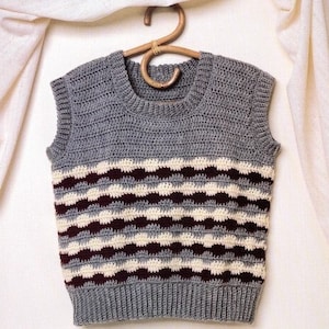 May include: A gray sleeveless crocheted vest with white and burgundy stripes. The vest has a round neckline and a textured pattern.