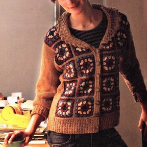 May include: A tan cardigan sweater with a patchwork design. The front panels feature square crochet patterns in red, blue, and white. The sweater has a collared neckline and button closure. The sleeves and back are a solid tan color.