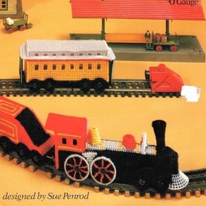 Puede incluir: La portada de un "TRAIN BOOK" muestra una maqueta de tren. Incluye un vagón amarillo, una locomotora roja y una estación roja. El texto "O Gauge" es visible. Las palabras "designed by Sue Penrod" están en la parte inferior de la imagen.