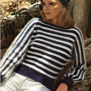 May include: A woman wearing a blue and white striped sweater with a blue headscarf. The sweater has a loose fit and long sleeves.