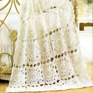 Puede incluir: Manta de ganchillo blanca con un delicado patrón floral. La manta está hecha con un punto de encaje y tiene una sensación suave y aireada.