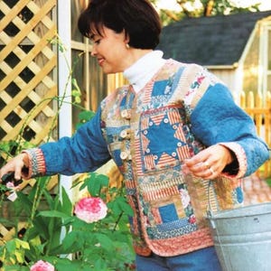 May include: A quilted jacket with blue sleeves and a patchwork front featuring star and square patterns. The jacket has a button closure and is worn with a white turtleneck and blue jeans. The scene is set outdoors with a garden and a metal bucket.