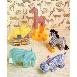 May include: Five stuffed animal toys: a pink and white horse, a yellow lion, a black and white zebra, a blue and white striped elephant, and a blue and white paisley hippopotamus. The toys are arranged on a light brown background with a pattern of giraffes and zebras.
