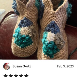 Puede incluir: Un par de zapatillas de crochet con un patr&oacute;n vintage. Las zapatillas est&aacute;n hechas con hilo marr&oacute;n, azul, blanco y turquesa. Las zapatillas tienen una superficie texturizada con peque&ntilde;os bultos.