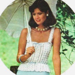 May include: A white crochet top with a delicate lace pattern. The top has a square neckline and thin straps. The model is wearing the top with a white crocheted hat and blue jeans.