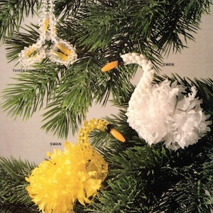 May include: Christmas tree decorations, featuring a three-point star and two swan designs. The star is made of clear beads with yellow accents. One swan is white, and the other is yellow, both with orange beaks. The text "THREE POINT STAR" and "SWAN" are visible.