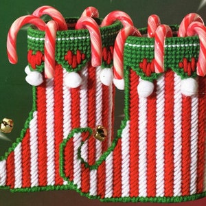 May include: Two red and white striped elf boot ornaments with green trim and white pom-poms. Each boot is filled with candy canes.