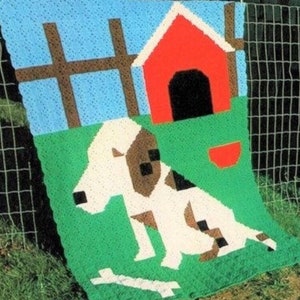 May include: A crocheted blanket featuring a white dog with brown spots, a red doghouse, and a green grassy area. The dog is sitting next to a white bone. The blanket is against a blue sky with brown fence posts.