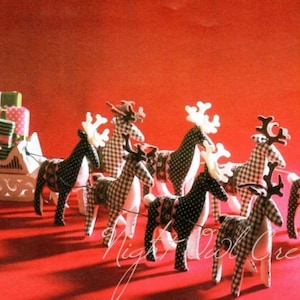 May include: A white wooden sleigh with a pink bow and green and white wrapped presents is pulled by eight black and white plaid reindeer with white antlers.