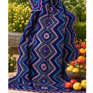 May include: A dark blue crochet blanket featuring a repeating diamond pattern with integrated floral motifs in shades of pink, teal, and purple. The edges are finished with a scalloped border, and the fabric displays a textured, yarn-based construction.