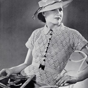 May include: A woman wearing a white crocheted top with a white crocheted hat. The top has a lace pattern and a button-up front. The hat has a wide brim and a ribbon.