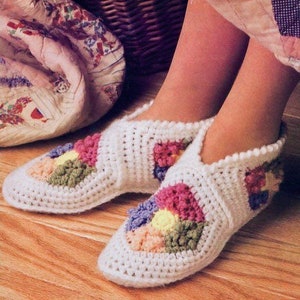 May include: White crocheted slippers with a colorful patchwork design. The slippers feature a geometric pattern with shades of pink, yellow, green, and purple.