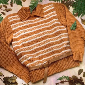 May include: A brown and white striped crocheted sweater with a brown leather belt. The sweater has a turtleneck collar and long sleeves.