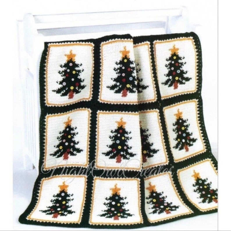 May include: A crocheted blanket with a repeating pattern of Christmas trees. The trees are green with brown trunks and have gold stars and colorful ornaments. The blanket is white with black borders around each tree.