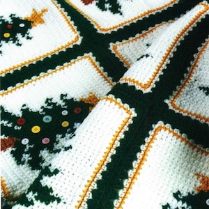 May include: A white crocheted blanket with a green and orange pattern of Christmas trees. The blanket is made with a variety of stitches and textures.