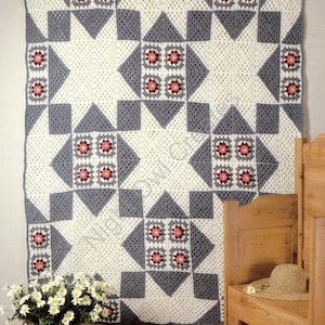 May include: A crocheted throw blanket with a star pattern in white and grey with pink flower accents.