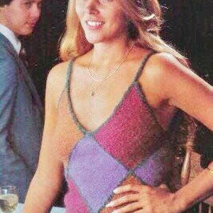 May include: A woman wearing a crocheted tank top with a diamond pattern in shades of purple, pink, and brown. The top has a V-neckline and thin straps.
