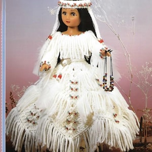May include: A handmade doll wearing a white crocheted dress with fringe and decorative beads. The doll has black hair, a beaded headband, and a beaded necklace. The dress features red and blue accents.