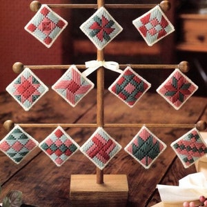 May include: A wooden stand with 10 square-shaped ornaments. The ornaments are made of fabric and have a patchwork design with red, green, and blue colors.