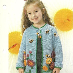 Puede incluir: Un c&aacute;rdigan de punto azul claro con ribetes verdes y aplicaciones de abejas y flores. El c&aacute;rdigan lo lleva una ni&ntilde;a peque&ntilde;a con el pelo largo y casta&ntilde;o.