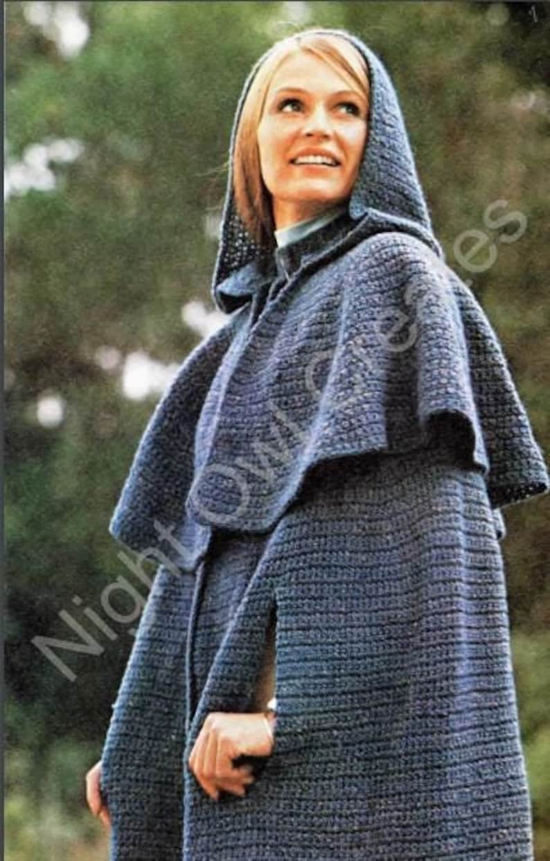 K&ouml;nnte beinhalten: Eine blaue, geh&auml;kelte Kapuzenjacke mit langem, flie&szlig;endem Design. Die Jacke hat einen breiten Kragen und eine spitze Kapuze. Die Jacke ist aus weichem, strukturiertem Garn gefertigt.