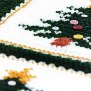 May include: A white crocheted blanket with a green crocheted Christmas tree design. The tree is decorated with colorful buttons.