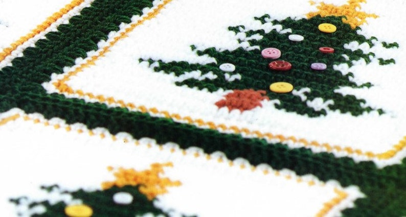 May include: A white crocheted blanket with a green crocheted Christmas tree design. The tree is decorated with colorful buttons.