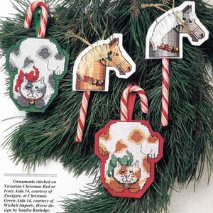 May include: Four handmade Christmas ornaments, each featuring a different design. A white cat with a red Santa hat, a brown and white horse, a white cat with a green bow, and a brown and white cat with a green bow. Each ornament is attached to a red and white candy cane.