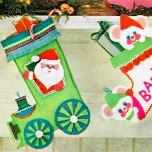 May include: Two Christmas stockings, one green and one white, decorated with felt appliqués. The green stocking is shaped like a train with a Santa Claus design. The white stocking has the word "BABY" and a mouse design.