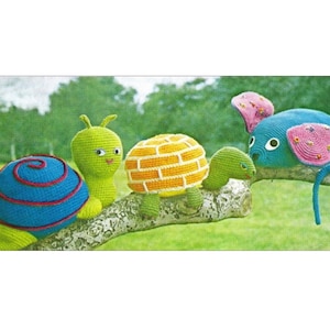 May include: A crocheted snail, turtle, and mouse on a tree branch. The snail is blue and red, the turtle is orange and white, and the mouse is blue and pink.
